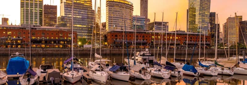 Puerto Madero al atardecer en Buenos Aires con barcos amarrados y reflejos sobre el agua